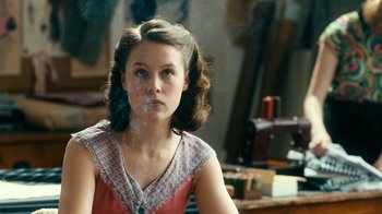 Movie still from “Never Look Away” (2018), directed by Florian Henckel von Donnersmarck – A young woman smoking a cigarette while sitting in a chair; Close Up shot, Over the shoulder angle