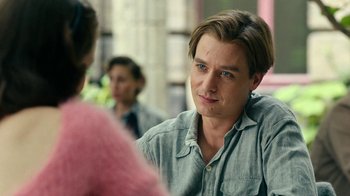 Movie still from “Never Look Away” (2018), directed by Florian Henckel von Donnersmarck – A man sitting in front of another man in front of another woman; Close Up shot, Over the shoulder angle