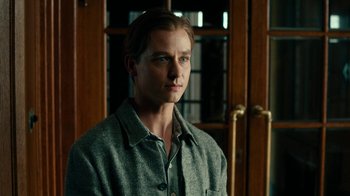 Movie still from “Never Look Away” (2018), directed by Florian Henckel von Donnersmarck – A man in a gray shirt is standing in front of a door; Close Up shot, Over the shoulder angle