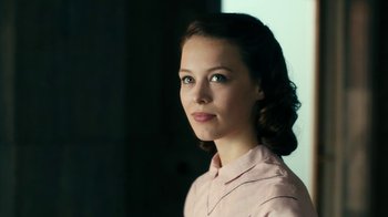 Movie still from “Never Look Away” (2018), directed by Florian Henckel von Donnersmarck – A young woman in a pink shirt is looking at the camera; Close Up shot, Over the shoulder angle
