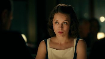 Movie still from “Never Look Away” (2018), directed by Florian Henckel von Donnersmarck – A young woman is sitting in a dark room; Close Up shot, Over the shoulder angle