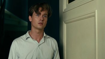 Movie still from “Never Look Away” (2018), directed by Florian Henckel von Donnersmarck – A man standing in front of a door looking to his left; Close Up shot, Low angle