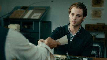 Movie still from “Never Look Away” (2018), directed by Florian Henckel von Donnersmarck – A man sitting at a dining table holding a paper; Close Up shot, Over the shoulder angle