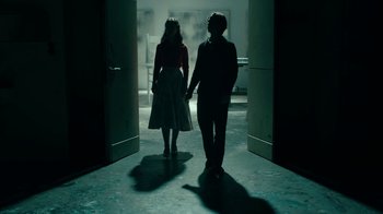 Movie still from “Never Look Away” (2018), directed by Florian Henckel von Donnersmarck – Two people are holding hands in a dark room; Wide shot, Low angle