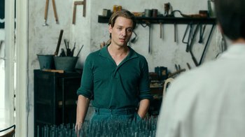 Movie still from “Never Look Away” (2018), directed by Florian Henckel von Donnersmarck – A man standing in front of a bunch of tools; Medium shot, Over the shoulder angle