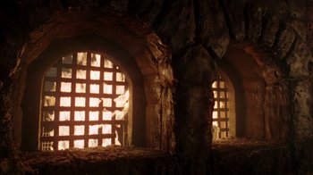 Movie still from “New Nightmare” (1994), directed by Wes Craven – A stone wall with two windows in the middle of it; Extreme Wide shot, Low angle