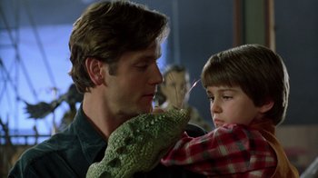 Movie still from “New Nightmare” (1994), directed by Wes Craven – A man and a boy are holding a lizard; Close Up shot, Over the shoulder angle