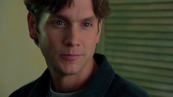 Movie still from “New Nightmare” (1994), directed by Wes Craven – A man's face in a black shirt; Close Up shot, Over the shoulder angle