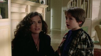 Movie still from “New Nightmare” (1994), directed by Wes Craven – A woman sitting next to a young boy in a room; Medium shot, Over the shoulder angle