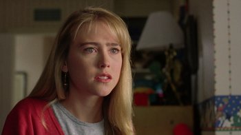 Movie still from “New Nightmare” (1994), directed by Wes Craven – A woman with blonde hair and a gray shirt is looking to her left; Close Up shot, Over the shoulder angle