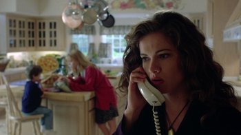 Movie still from “New Nightmare” (1994), directed by Wes Craven – A woman is talking on a phone in a kitchen; Close Up shot, Low angle