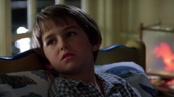 Movie still from “New Nightmare” (1994), directed by Wes Craven – A young boy sitting on a couch in a living room; Close Up shot, High angle