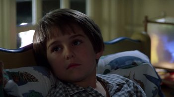 Movie still from “New Nightmare” (1994), directed by Wes Craven – A young boy sitting on a couch looking at the camera; Close Up shot, Low angle