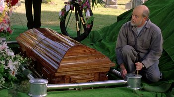 Movie still from “New Nightmare” (1994), directed by Wes Craven – An older man sitting next to a wooden casket; Medium shot, High angle