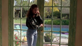 Movie still from “New Nightmare” (1994), directed by Wes Craven – A woman talking on a cell phone while standing in front of a pool; Medium shot, High angle