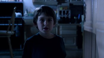 Movie still from “New Nightmare” (1994), directed by Wes Craven – A young boy standing in the dark in a kitchen; Close Up shot, Over the shoulder angle