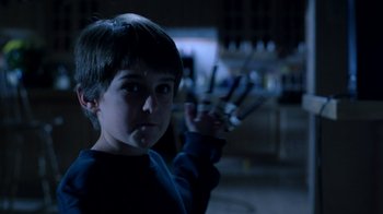 Movie still from “New Nightmare” (1994), directed by Wes Craven – A young boy holding a pair of scissors in a dark room; Close Up shot, Low angle
