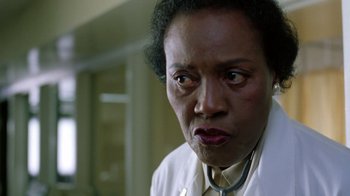 Movie still from “New Nightmare” (1994), directed by Wes Craven – An older woman wearing a white lab coat; Close Up shot, Low angle