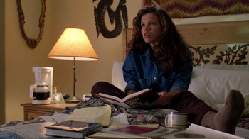 Movie still from “New Nightmare” (1994), directed by Wes Craven – A woman sitting on the floor reading a book; Medium shot, High angle