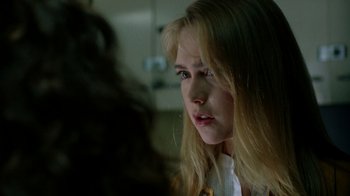 Movie still from “New Nightmare” (1994), directed by Wes Craven – A woman with long blonde hair stares into the camera; Close Up shot, Over the shoulder angle