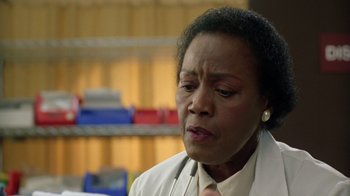 Movie still from “New Nightmare” (1994), directed by Wes Craven – An older black woman wearing a white shirt and tie; Close Up shot, Over the shoulder angle