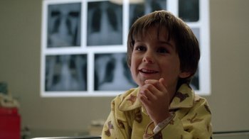 Movie still from “New Nightmare” (1994), directed by Wes Craven – A young boy wearing pajamas smiling for the camera; Close Up shot, Low angle