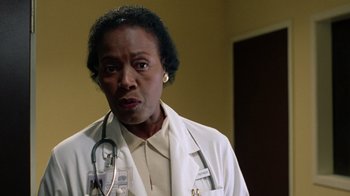 Movie still from “New Nightmare” (1994), directed by Wes Craven – A woman in a white lab coat with a stethoscope around her neck; Close Up shot, Low angle