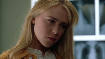 Movie still from “New Nightmare” (1994), directed by Wes Craven – A young blonde haired woman with long blonde hair; Close Up shot, Over the shoulder angle