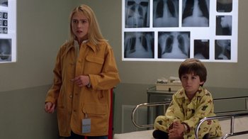Movie still from “New Nightmare” (1994), directed by Wes Craven – A woman and a boy are standing in front of a hospital bed; Medium shot, Low angle