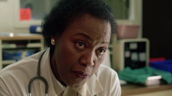 Movie still from “New Nightmare” (1994), directed by Wes Craven – An older woman with a stethoscope around her neck; Close Up shot, Low angle