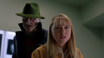 Movie still from “New Nightmare” (1994), directed by Wes Craven – A woman wearing a green hat standing next to a man wearing a yellow jacket; Close Up shot, Over the shoulder angle