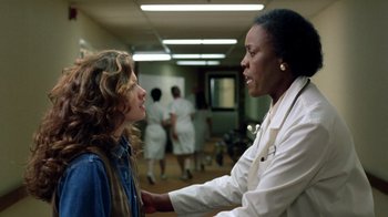Movie still from “New Nightmare” (1994), directed by Wes Craven – A doctor talking to a patient in a hospital room; Medium shot, Low angle
