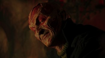 Movie still from “New Nightmare” (1994), directed by Wes Craven – The face of a person wearing a mask; Close Up shot, Low angle