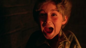 Movie still from “New Nightmare” (1994), directed by Wes Craven – A young boy is making a funny face with his mouth open; Close Up shot, Overhead angle