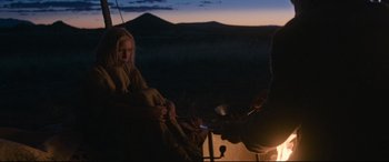 Movie still from “News of the World” (2020), directed by Paul Greengrass – A woman sitting in a chair next to a campfire; Wide shot, Over the shoulder angle