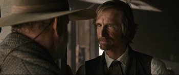 Movie still from “News of the World” (2020), directed by Paul Greengrass – A man in a cowboy hat looking at another man in a suit; Close Up shot, Over the shoulder angle