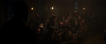 Movie still from “News of the World” (2020), directed by Paul Greengrass – A group of people sitting in a dark room; Wide shot, High angle