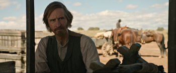 Movie still from “News of the World” (2020), directed by Paul Greengrass – A man with a beard and a vest standing in front of a horse; Close Up shot, Over the shoulder angle