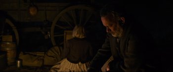 Movie still from “News of the World” (2020), directed by Paul Greengrass – A man and a woman sitting next to each other in a dark room; Medium shot, High angle