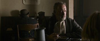 Movie still from “News of the World” (2020), directed by Paul Greengrass – An older man sitting at a table with a plate of food in front of him; Medium shot, Low angle