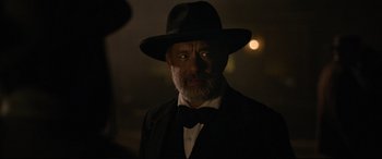 Movie still from “News of the World” (2020), directed by Paul Greengrass – An older man wearing a hat and a bow tie; Close Up shot, Over the shoulder angle