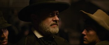 Movie still from “News of the World” (2020), directed by Paul Greengrass – An old man with a beard wearing a hat; Close Up shot, Over the shoulder angle