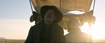 Movie still from “News of the World” (2020), directed by Paul Greengrass – An older man and a young girl under an awning; Medium shot, Low angle