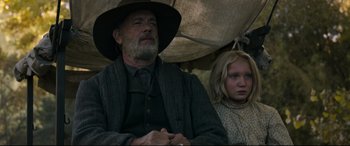 Movie still from “News of the World” (2020), directed by Paul Greengrass – An older man and a young girl sitting next to each other; Medium shot, Low angle