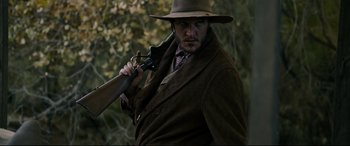 Movie still from “News of the World” (2020), directed by Paul Greengrass – A man holding a gun in a brown coat; Medium shot, Low angle