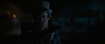 Movie still from “News of the World” (2020), directed by Paul Greengrass – A man in a top hat holding a gun in the dark; Close Up shot, Over the shoulder angle