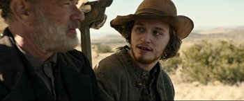 Movie still from “News of the World” (2020), directed by Paul Greengrass – A man with a hat and a beard standing next to another man; Close Up shot, Over the shoulder angle