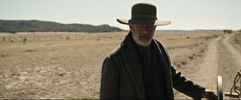 Movie still from “News of the World” (2020), directed by Paul Greengrass – An old man with a beard and a hat in the middle of the desert; Medium shot, Over the shoulder angle