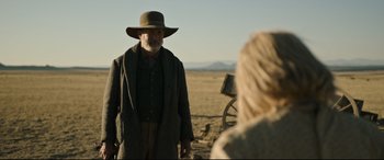 Movie still from “News of the World” (2020), directed by Paul Greengrass – An older man in a hat and a long coat standing next to a woman; Medium shot, Over the shoulder angle