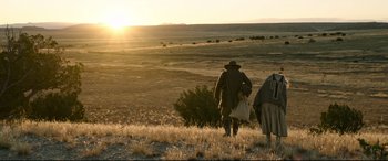 Movie still from “News of the World” (2020), directed by Paul Greengrass – A man and a woman walking across a field at sunset; Extreme Wide shot, Low angle